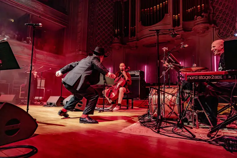 Danseur et musiciens sur une scène baignée de rouge